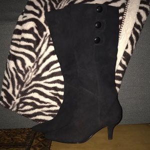 Knee high black boots with button embellishments.